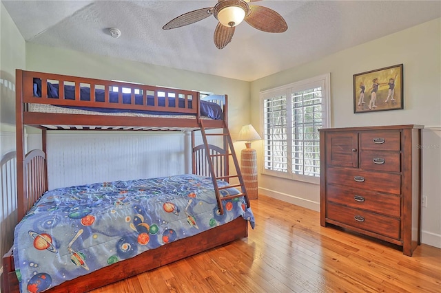 bedroom featuring light hardwood / wood-style floors, ceiling fan, and a textured ceiling