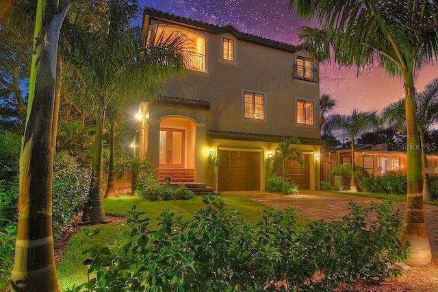 mediterranean / spanish house with a garage, decorative driveway, and stucco siding