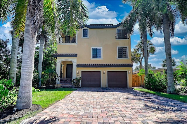 mediterranean / spanish-style house featuring decorative driveway, fence, an attached garage, and stucco siding