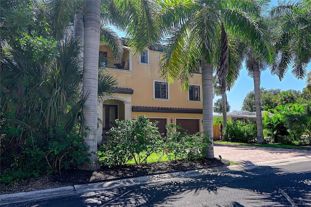 view of front of property featuring decorative driveway, an attached garage, and stucco siding