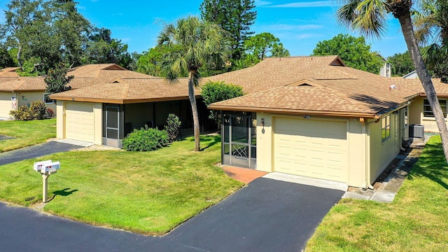 single story home featuring cooling unit, a front yard, and a garage