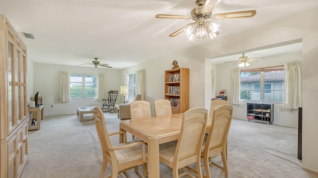 dining space featuring a textured ceiling, light carpet, and ceiling fan