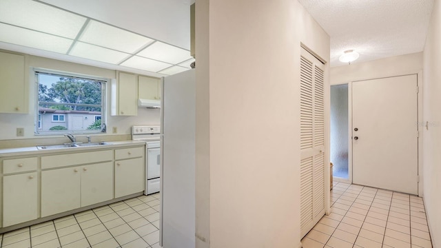 kitchen featuring white range oven, sink, and light tile patterned floors