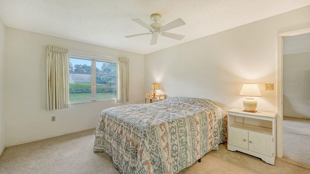 bedroom with ceiling fan, light colored carpet, and a textured ceiling