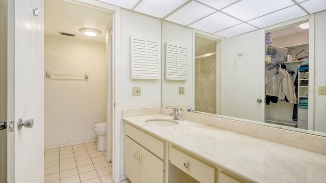 bathroom with tile patterned flooring, a paneled ceiling, vanity, and toilet