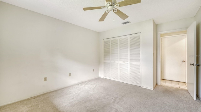 unfurnished bedroom with ceiling fan, light colored carpet, and a closet