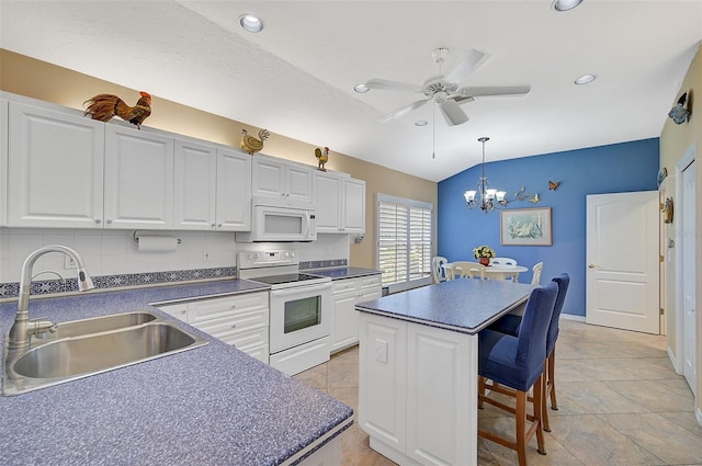 kitchen featuring ceiling fan with notable chandelier, white appliances, a center island, decorative light fixtures, and sink