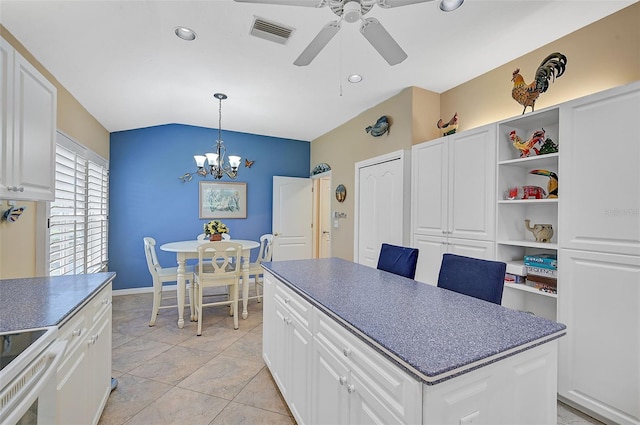 kitchen with lofted ceiling, light tile patterned floors, decorative light fixtures, white cabinetry, and ceiling fan with notable chandelier