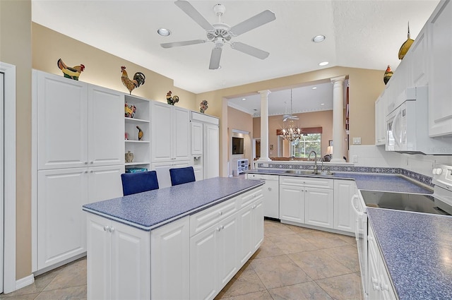 kitchen with ceiling fan with notable chandelier, white appliances, white cabinetry, and ornate columns