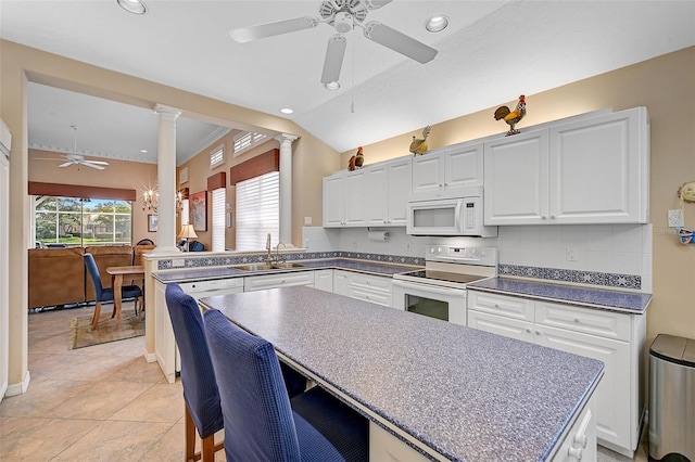 kitchen with ceiling fan, sink, white appliances, a kitchen island, and decorative columns