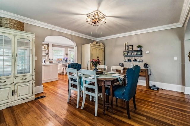 dining space featuring wood-type flooring, crown molding, and a notable chandelier