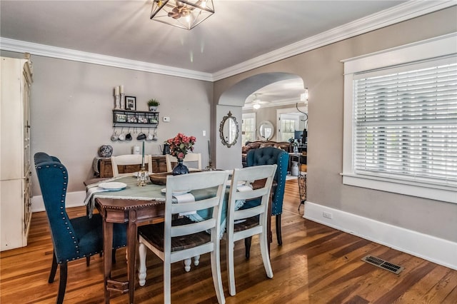 dining space with wood-type flooring, a chandelier, ornamental molding, and a wealth of natural light