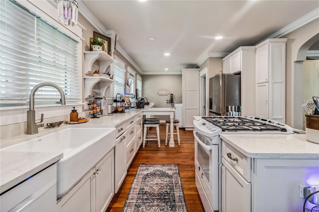 kitchen with stainless steel fridge, sink, dark wood-type flooring, white gas range, and white cabinetry