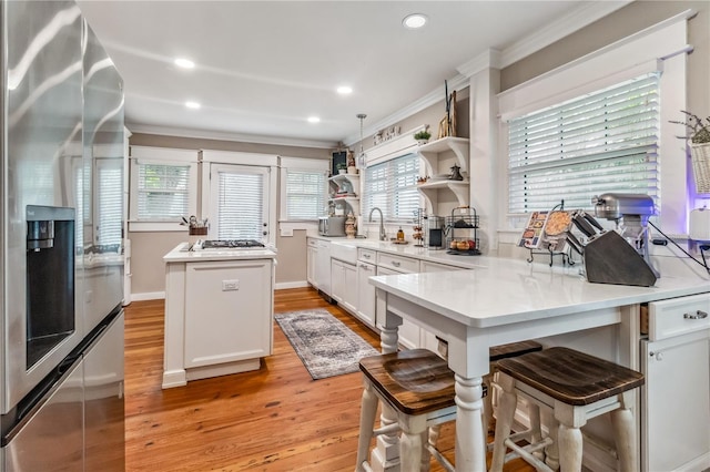 kitchen with light hardwood / wood-style flooring, stainless steel appliances, white cabinetry, and a wealth of natural light