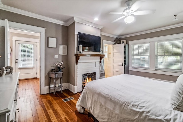 bedroom with ornamental molding, ceiling fan, dark hardwood / wood-style floors, and a fireplace