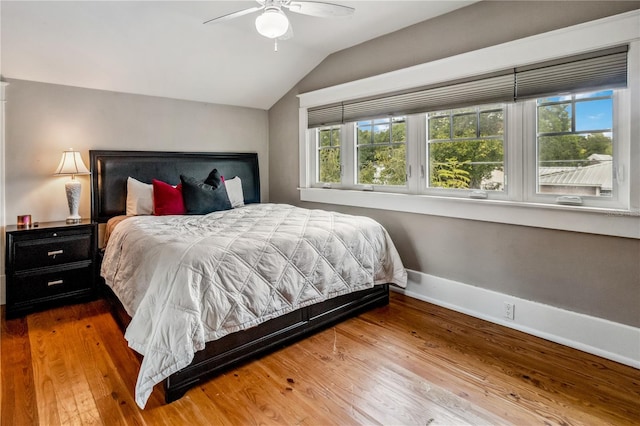 bedroom featuring multiple windows, lofted ceiling, ceiling fan, and hardwood / wood-style flooring