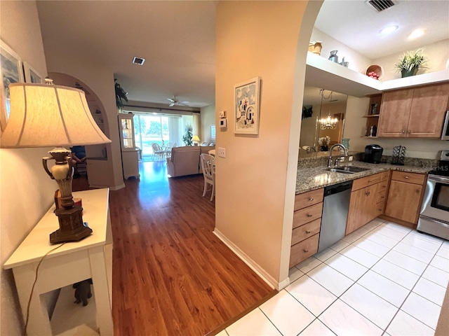 kitchen with sink, light hardwood / wood-style flooring, stainless steel appliances, light stone countertops, and ceiling fan