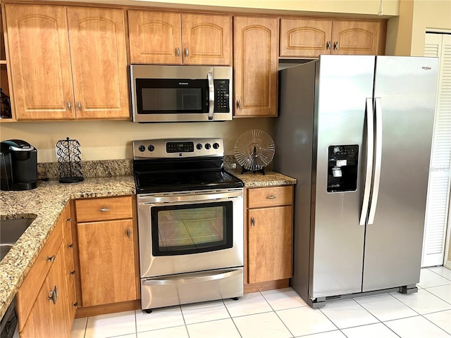 kitchen with appliances with stainless steel finishes, light stone countertops, and light tile patterned floors