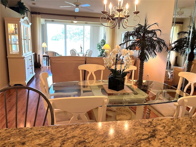 dining area featuring a textured ceiling, ceiling fan with notable chandelier, and dark hardwood / wood-style flooring