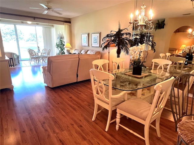 dining space with ceiling fan with notable chandelier and dark hardwood / wood-style flooring