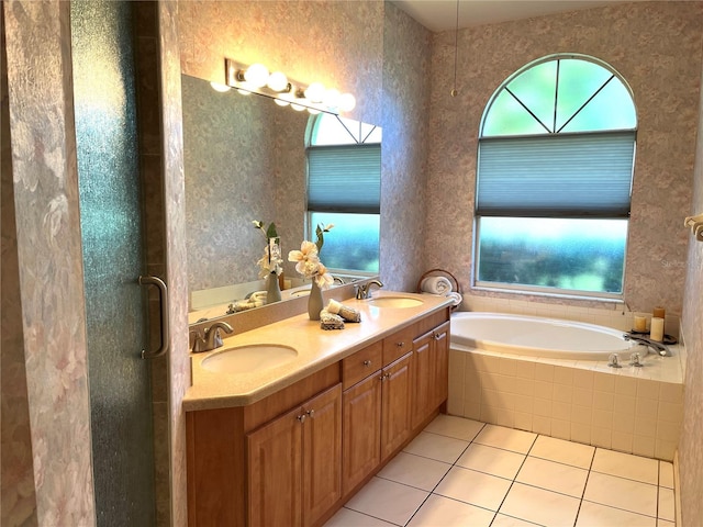 bathroom featuring tile patterned flooring, tiled bath, and vanity