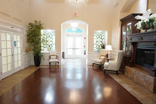 entryway featuring french doors, hardwood / wood-style flooring, a fireplace, and a towering ceiling