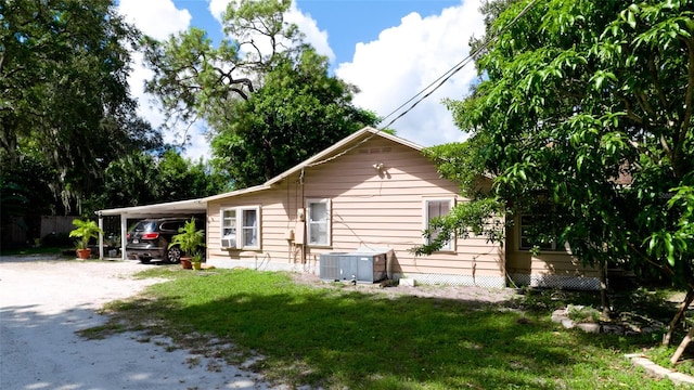 view of side of property featuring cooling unit, a yard, and a carport