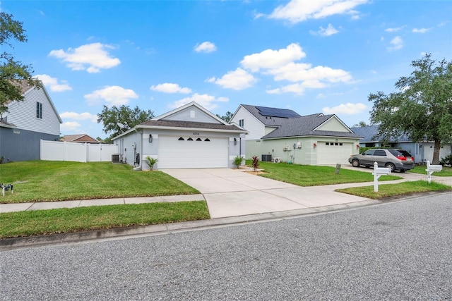 view of front of home with a front lawn, central AC unit, and a garage