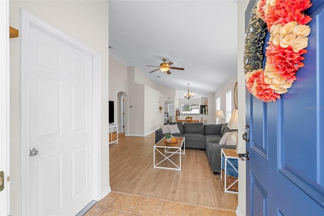 living room featuring ceiling fan with notable chandelier, lofted ceiling, and light wood-type flooring