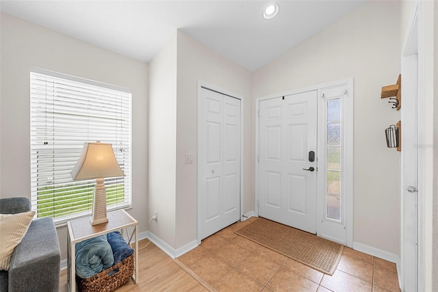 entryway with lofted ceiling and light tile patterned floors