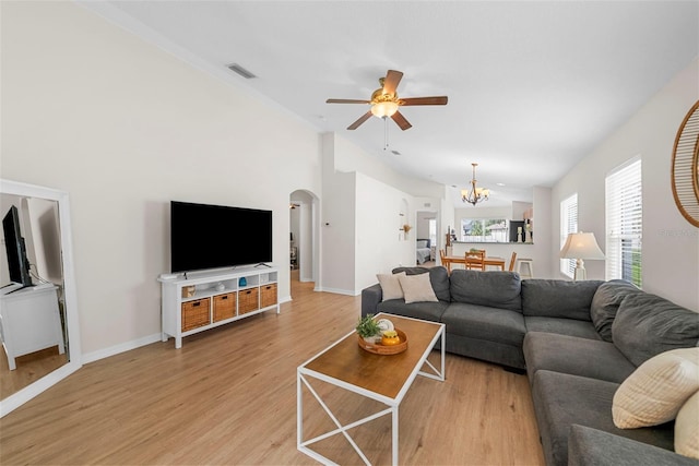 living room featuring wood-type flooring, ceiling fan with notable chandelier, and vaulted ceiling