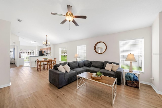 living room with ceiling fan with notable chandelier, lofted ceiling, and a healthy amount of sunlight