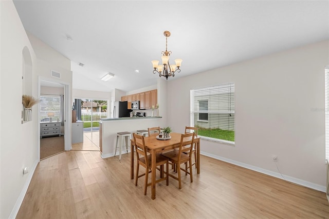 dining room with a notable chandelier, lofted ceiling, and light hardwood / wood-style floors