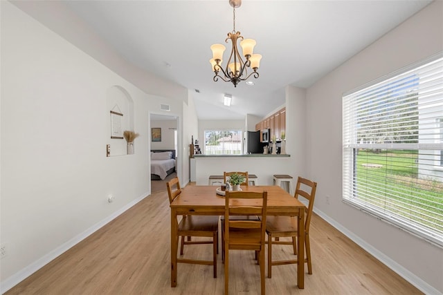 dining area featuring light hardwood / wood-style flooring, lofted ceiling, and a chandelier