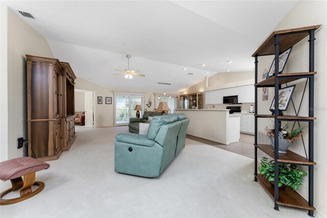 living room with lofted ceiling, ceiling fan, and light colored carpet