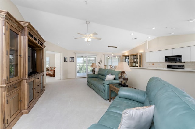 living room with vaulted ceiling, ceiling fan, and light colored carpet