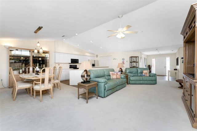 living room with ceiling fan with notable chandelier, vaulted ceiling, and light carpet