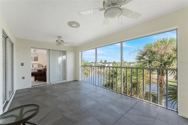 unfurnished sunroom with a water view and ceiling fan