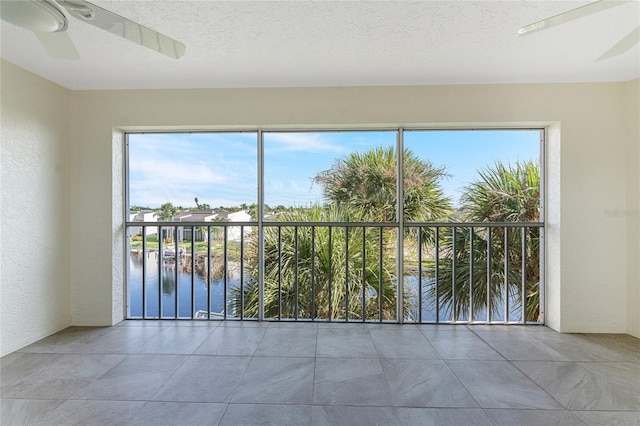 unfurnished room featuring a textured ceiling, a water view, and ceiling fan