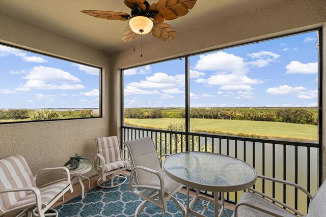 sunroom / solarium with ceiling fan and a rural view