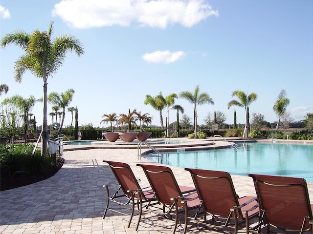 view of swimming pool featuring a patio and a hot tub