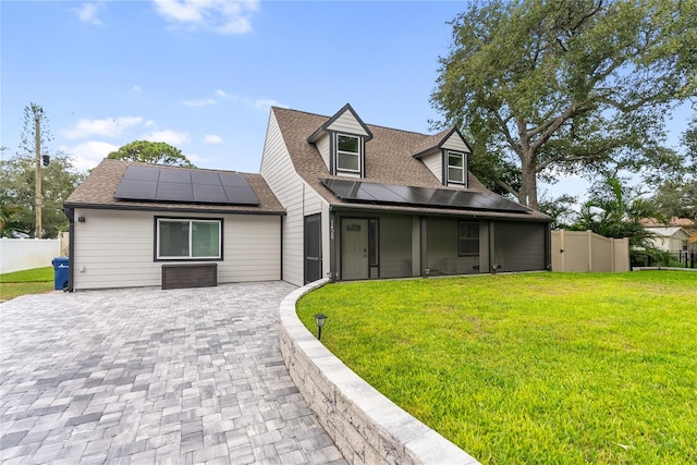 cape cod home featuring solar panels, a front lawn, and a patio area