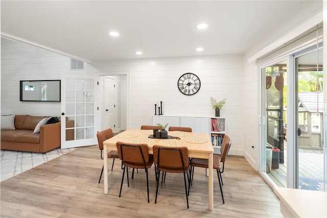 dining area featuring wooden walls and light hardwood / wood-style flooring