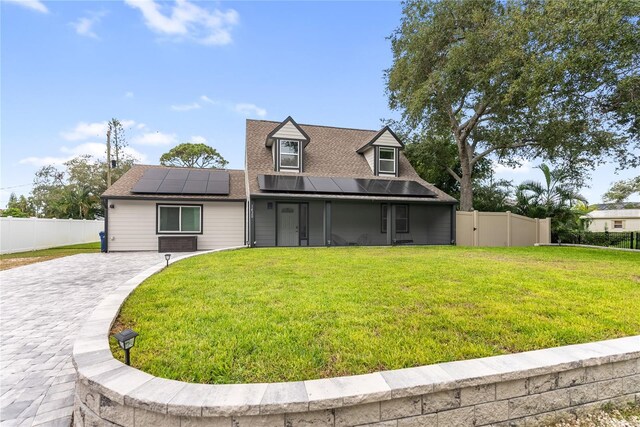 cape cod home with a front yard and solar panels