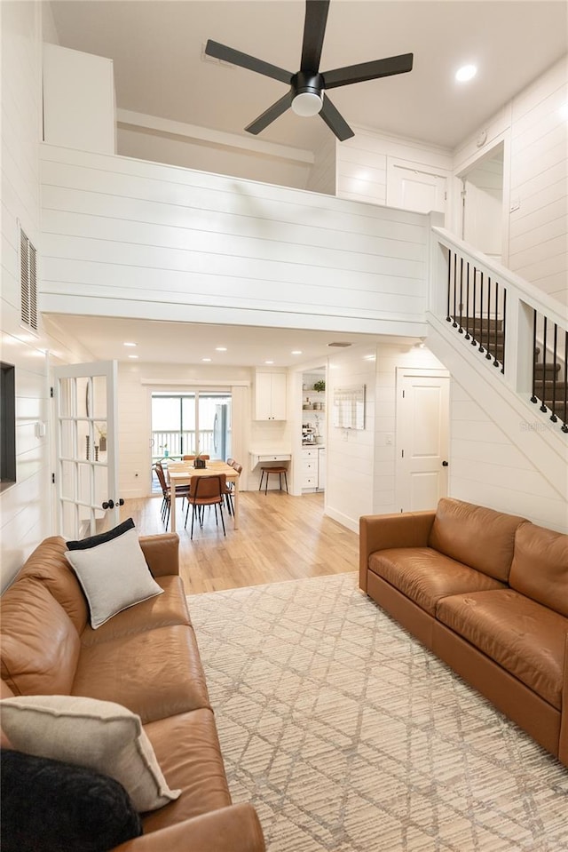 living room featuring ceiling fan, light wood-type flooring, and a high ceiling