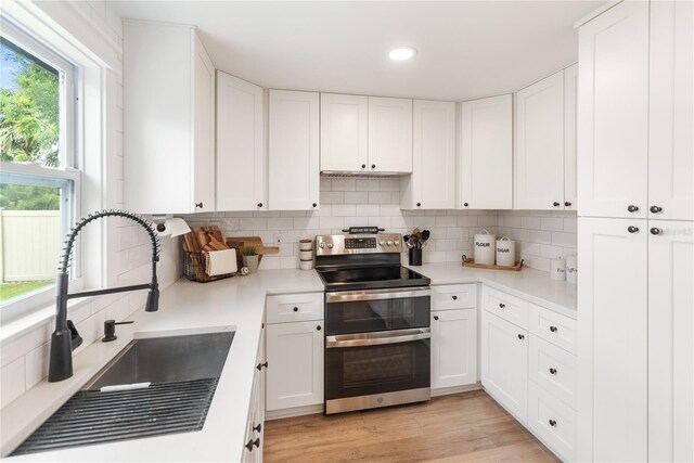 kitchen featuring white cabinets, sink, tasteful backsplash, electric range, and light hardwood / wood-style floors