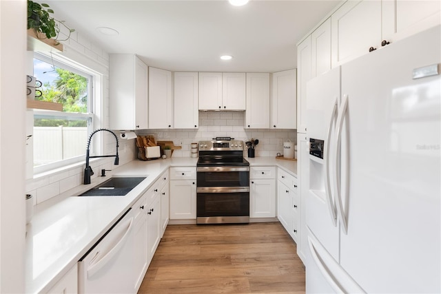 kitchen featuring white cabinets, sink, white appliances, light hardwood / wood-style flooring, and backsplash