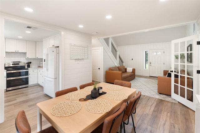 dining area with light hardwood / wood-style flooring and wood walls