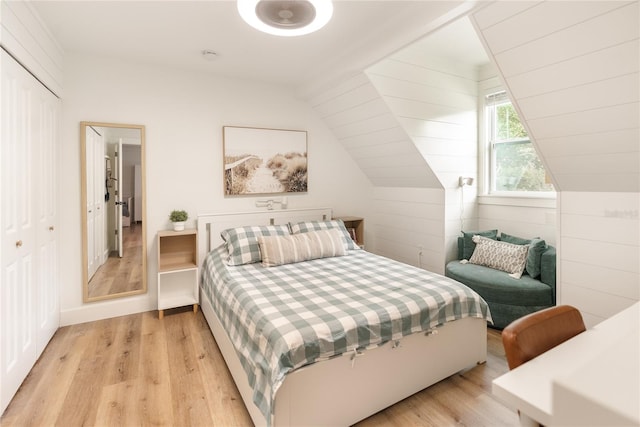 bedroom featuring light hardwood / wood-style floors, vaulted ceiling, and a closet