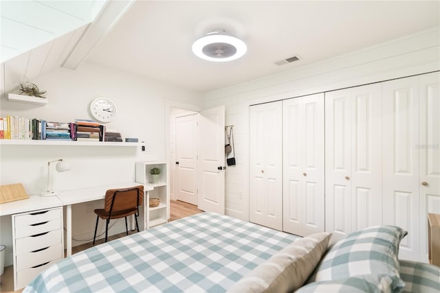 bedroom with vaulted ceiling with beams, light hardwood / wood-style floors, and a closet